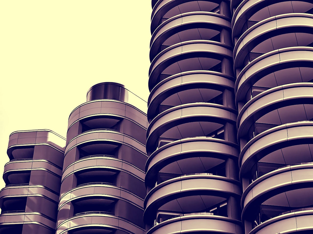 Stylish urban skyscraper perspective with circular balcony design and modern architecture.