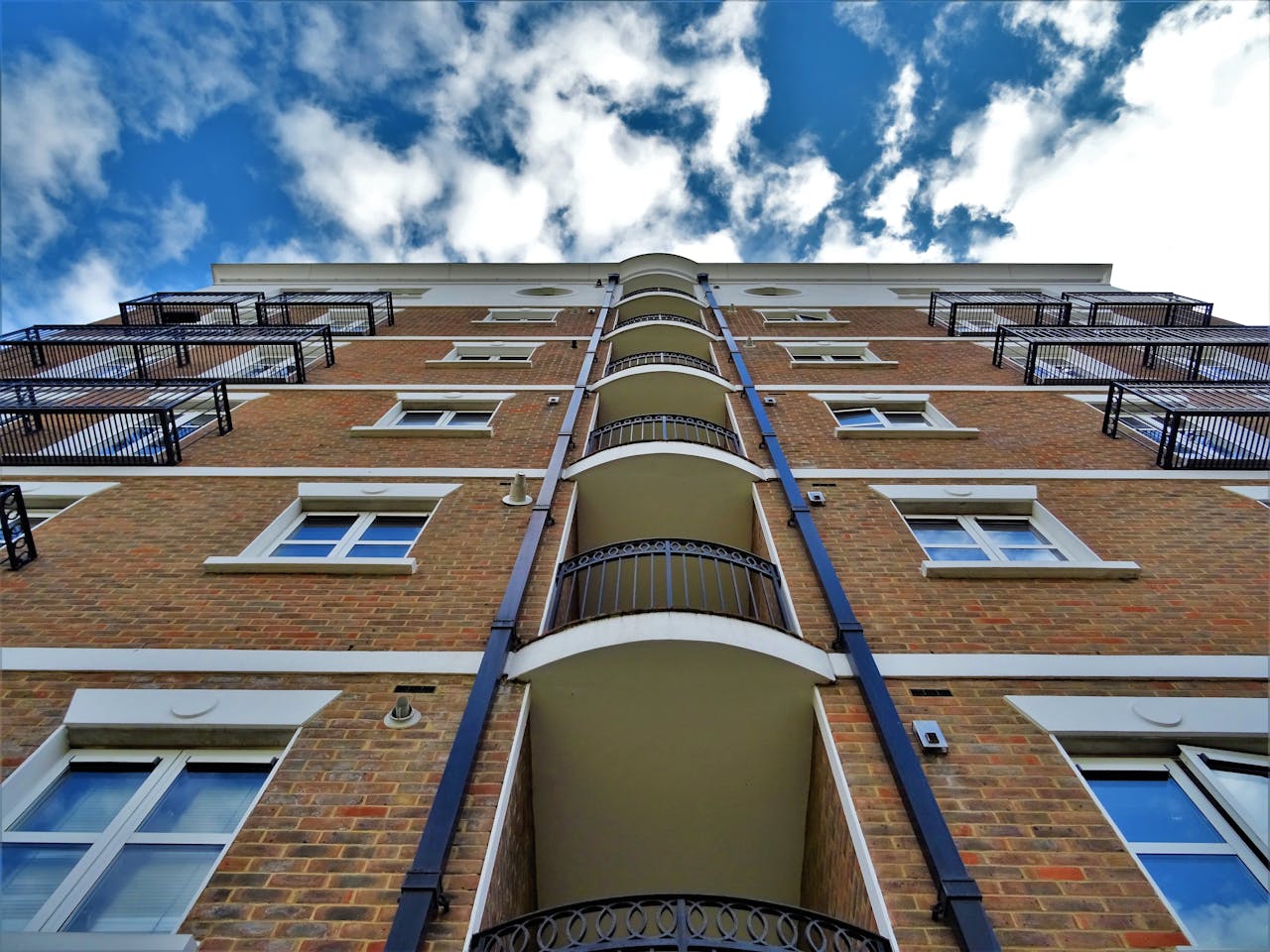 Low angle view of a modern urban apartment building with balconies under a clear blue sky.
