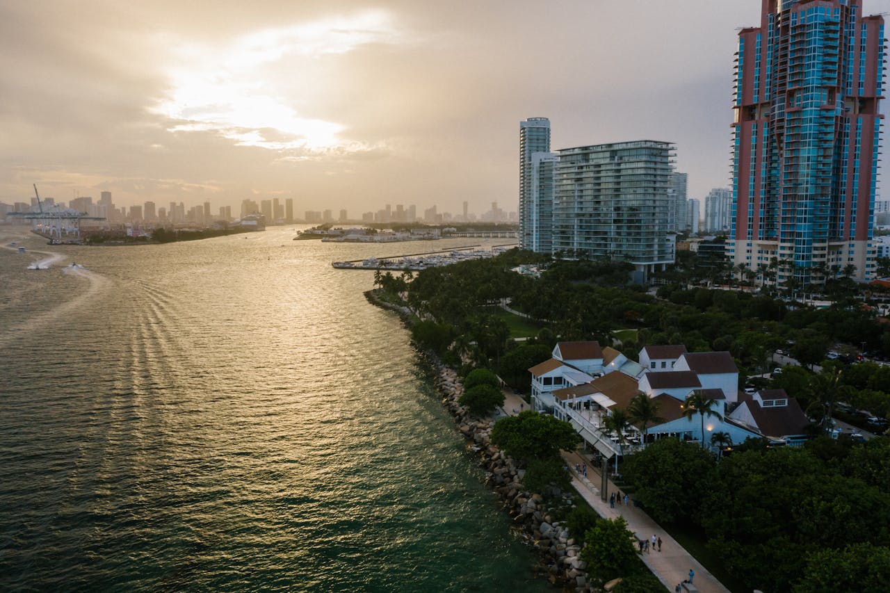 A breathtaking aerial view of a coastal city skyline at sunset with high rises and lush greenery.